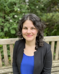 Photo of Masha Baryakhtar in blue shirt and black jacket looking at the camera